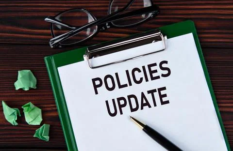 POLICIES UPDATE - words on a white sheet on a brown wooden background with .. Stock Photos