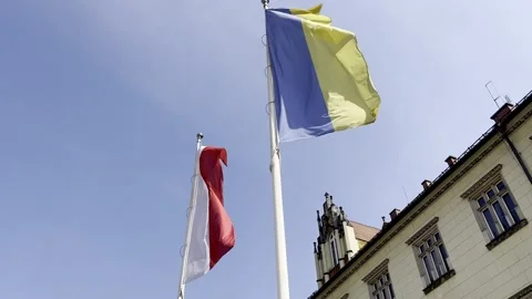 Polish and Ukrainian flags waving on flagpoles against blue sky Stock Footage 306068801
