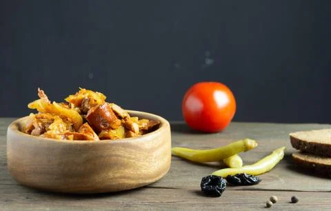 Polish dish bigos made from cabbage, meat and sausages. Bread, tomato, hot pe Stock Photos