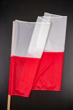 Polish flag on a dark table. A flag attached to a wooden spar. Stock Photos