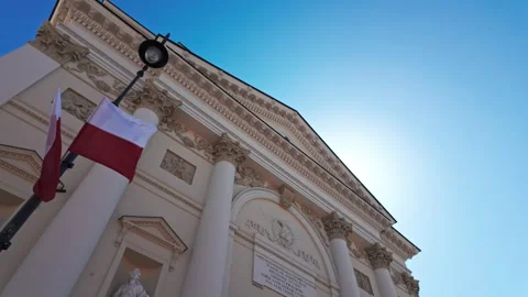 Polish flag flying in front of a classical building in Warsaw under clear blue Vídeos de archivo 309623769
