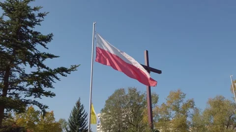 Polish flag waving beside mounted cross in outdoor park setting 스톡 동영상 342028041