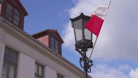 Polish flag waving in front of a building with a street lamp Stock Footage 309008534