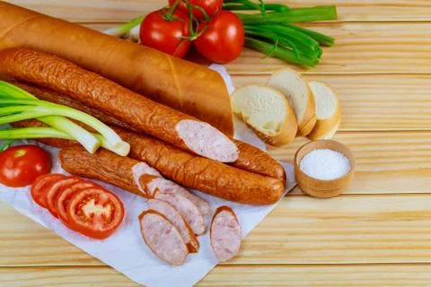 Polish kielbasa with vegetables and bread on wooden background. Stock Photos