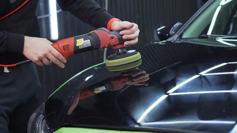 In polished bonnet of car, lighting of workshop and worker are reflected Stock Footage 115933096
