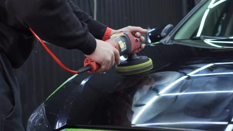 In polished bonnet of car, lighting of workshop and worker are reflected Stock Footage 115933140
