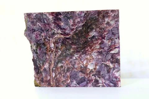 Polished charoite pattern on a white table. Stock Photos