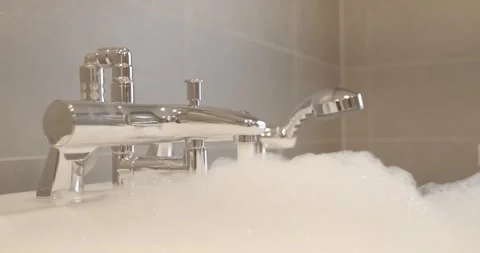 Polished Chrome Tap With Hand Shower Above Foam, Bathtub Edge, Macro Detail Stock Footage 340360468