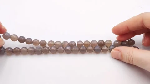 Polished gray agate gemstone beads presented on strands for jewelry crafting Stock Footage 345139631