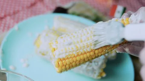 Polished kitchen study: turning coated corn for even coverage Stock Photos