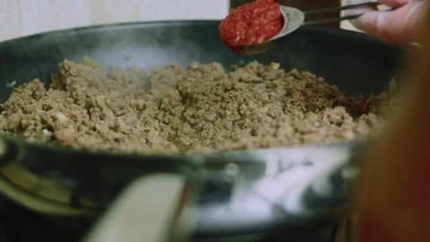 Polished tabletop view of spooning tomato paste into seasoned beef Stock Footage 342153376