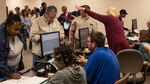 Poll worker points out voting terminals to male voter Free Stock Photos