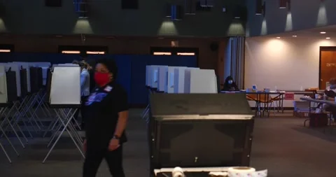 Poll worker walks thru frame while people vote in background, 11/3/20 election Stock Footage 152522133