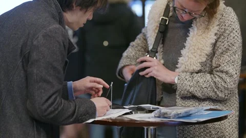 A polling official hands ballot papers to a voter Stock-Footage 345298981