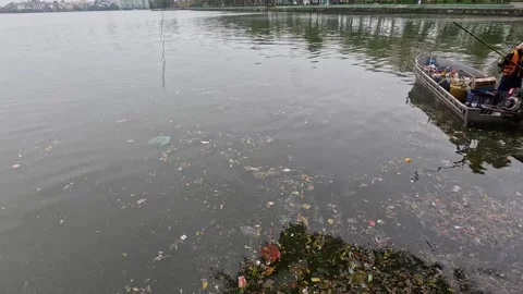 Polluted lake water with plastic waste and garbage collector worker on smal.. Stock Footage 332582081