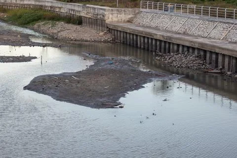 Polluted River with Debris and Low Water Level Stock Photos