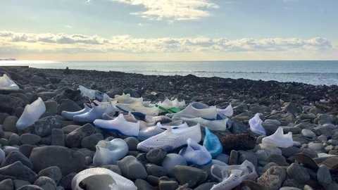 Polluted shore, garbage on the beach, empty plastic bottles, rubber shoes Stock Footage 121964959