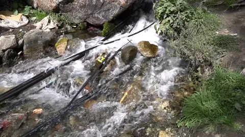 Polluted stream carrying trash and debris through rugged rocky terrain Video stock 330317144