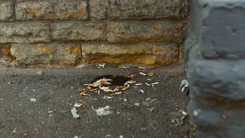 Polluted streets. Cigarette butts lying around by the corner. Stock Footage 157993166