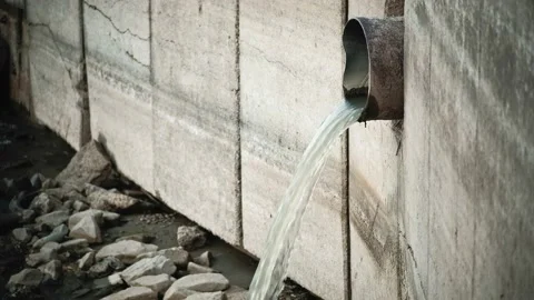 Polluted water flows out from the weathered pipe into the river, environmental Stockbeeldmateriaal 164408387