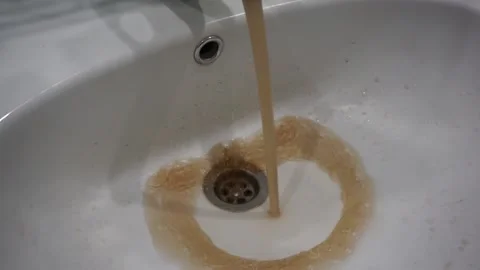 Pollution problems. Dirty rusty water flows from the tap into the sink Stock Footage 196925215
