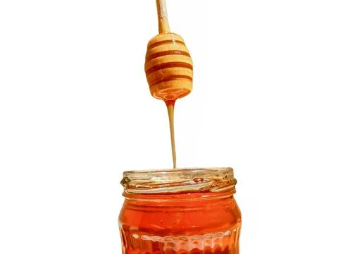 Polyflora bee honey flowing into a jar from a wooden spoon. The concept of be 库存照片