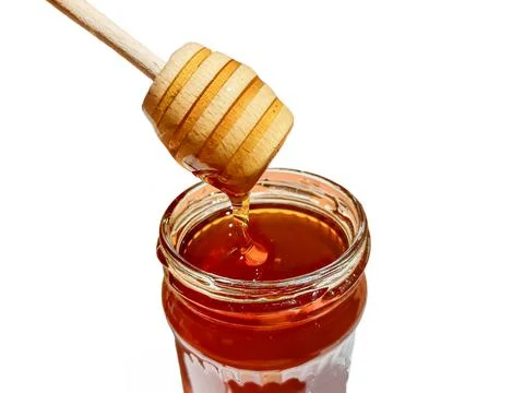 Polyflora bee honey flowing into a jar from a wooden spoon. The concept of be 库存照片