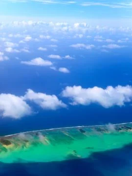 Polynesia. The atoll in ocean through clouds. Aerial view... Stock Photos