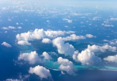 Polynesia. The atoll in ocean through clouds. Aerial view... Stock Photos
