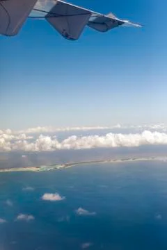 Polynesia. The atoll in ocean through clouds. Aerial view. Stock Photos