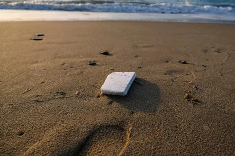 Polystyrene garbage on sandy sea shore on sunset golden light,pollution concept Stock Photos