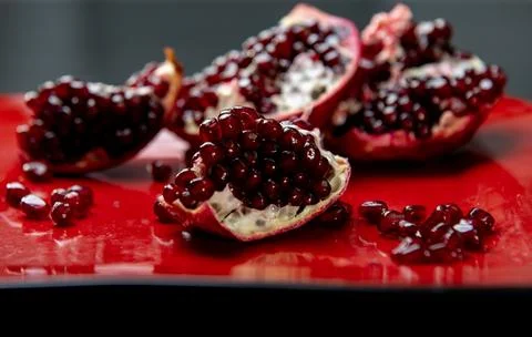 Pomegranate arils macro closeup on red plate. Fresh pomegranate seeds textu.. Stock Photos