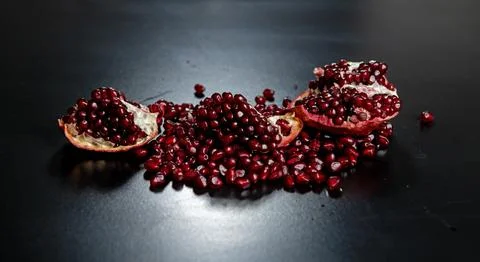 Pomegranate on black background. Pomegranate arils and halves. Healthy antiox 库存照片
