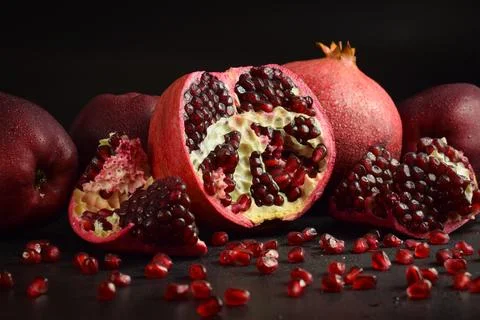 Pomegranate clusters with fresh pomegranate arils on black background Stock Photos