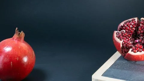Pomegranate fruit, on the right, the fruit is open on the stone kitchen board Stock Photos