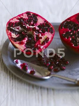 A pomegranate, halved and pomegranate seeds Stock Photos