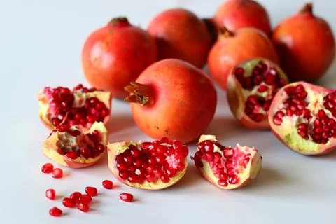 Pomegranate. Open fruit with glistening ruby red arils on a white surface, ca 스톡 사진