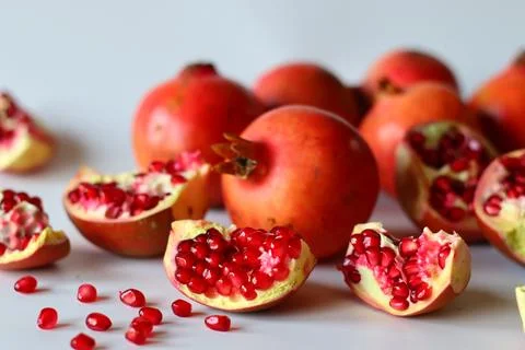 Pomegranate. Open fruit with glistening ruby red arils on a white surface, ca Foto stock
