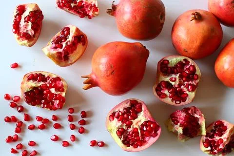 Pomegranate. Open fruit with glistening ruby red arils on a white surface, ca 스톡 사진