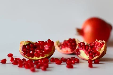 Pomegranate. Open fruit with glistening ruby red arils on a white surface, ca 写真素材