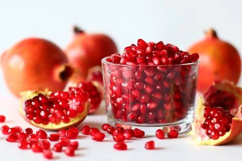 Pomegranate. Open fruit with glistening ruby red arils on a white surface 스톡 사진