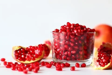 Pomegranate. Open fruit with glistening ruby red arils on a white surface Stock Photos