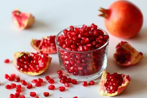 Pomegranate. Open fruit with glistening ruby red arils on a white surface 스톡 사진