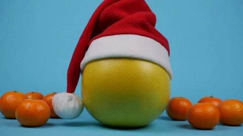 Pomelo in hat of santa claus with rolling tangerines near. Stop motion Stock-Footage 121093973