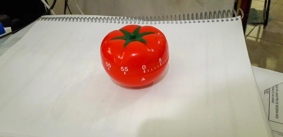 Pomodoro timer in background of paper textures piled. Stock Photos