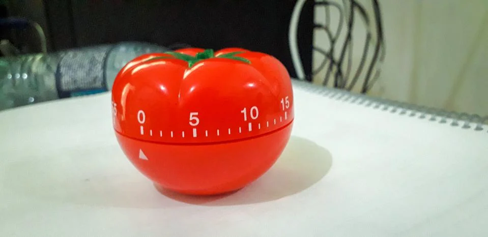 Pomodoro timer in background of paper textures piled. Stock Photos