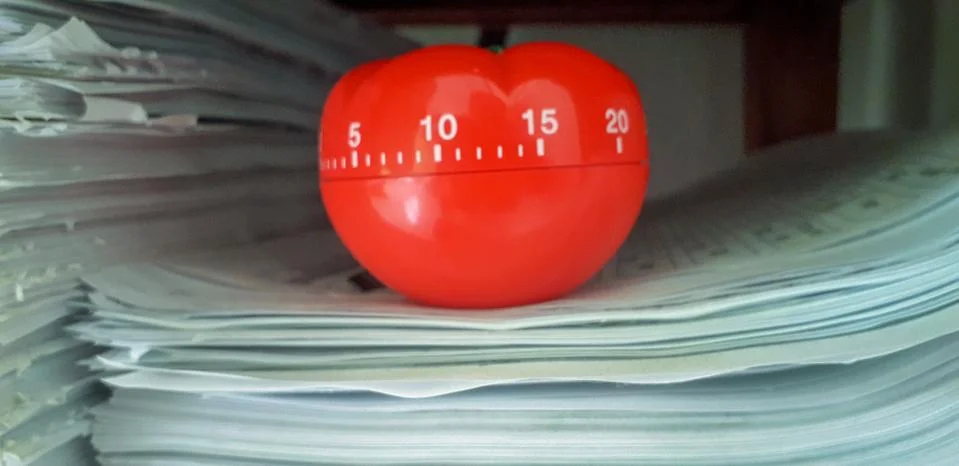 Pomodoro timer in background of paper textures piled. Stock Photos