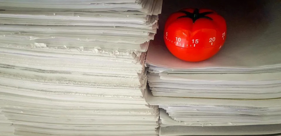 Pomodoro timer in background of paper textures piled. Stock Photos