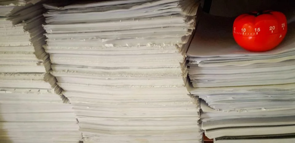 Pomodoro timer in background of paper textures piled. Stock Photos