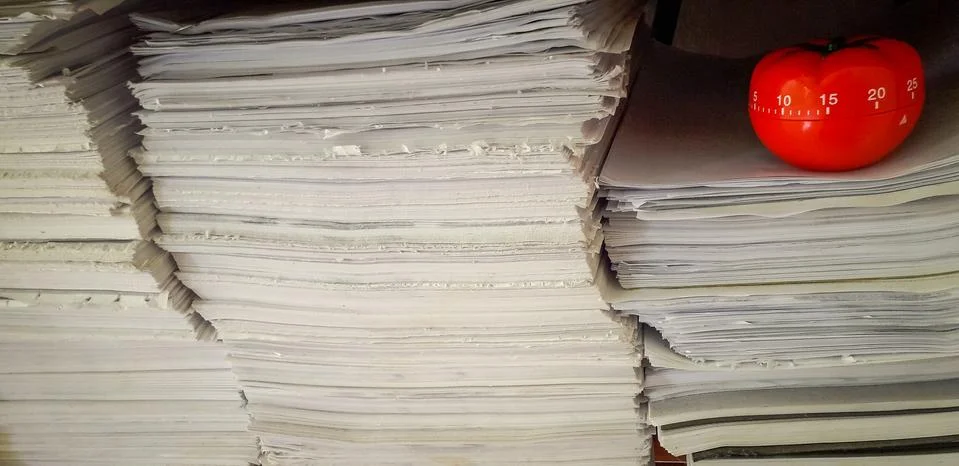 Pomodoro timer in background of paper textures piled. Stock Photos